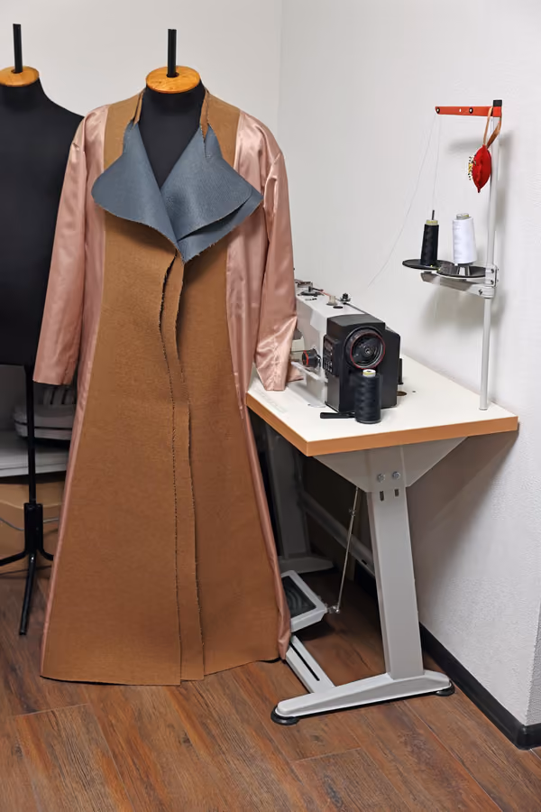 Tailored coat on a mannequin beside the sewing station