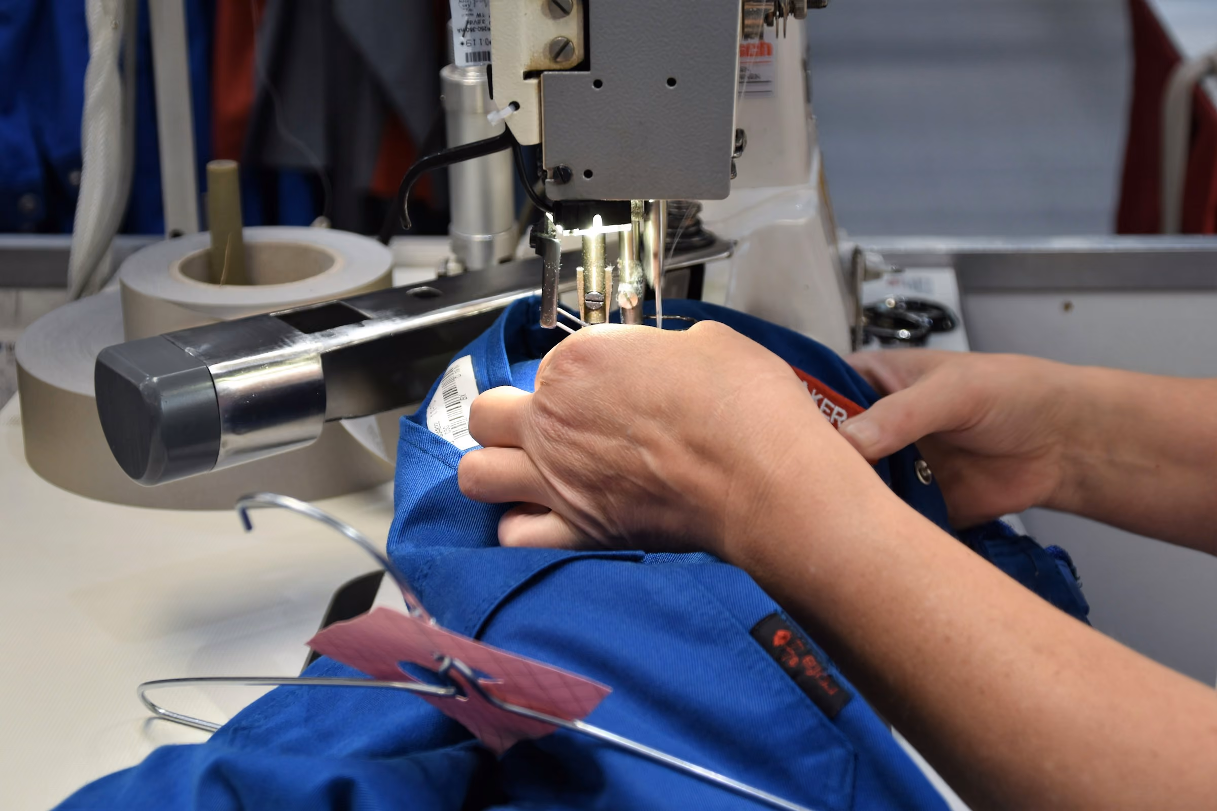 Hands guiding fabric through an industrial sewing machine during alterations