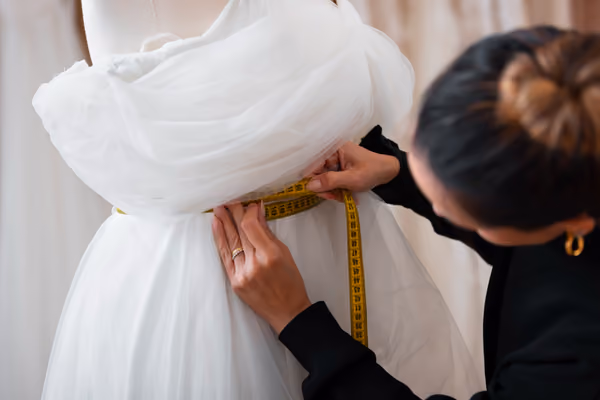 Measuring a bride's wedding dress for alterations